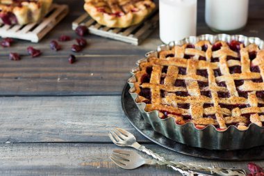 Traditional American cherry pie and mini pies on a dark wooden background clipart