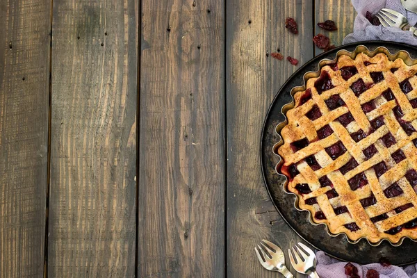 Traditional American cherry pie and mini pies on a dark wooden background