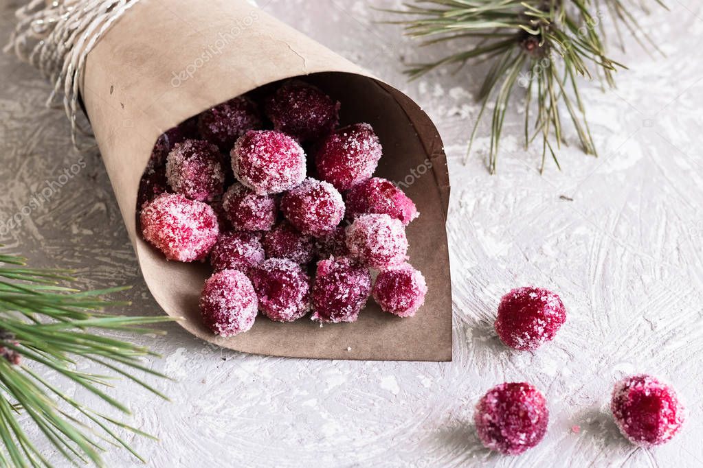 Candied cranberries in a crafting bag on the background of fir cones