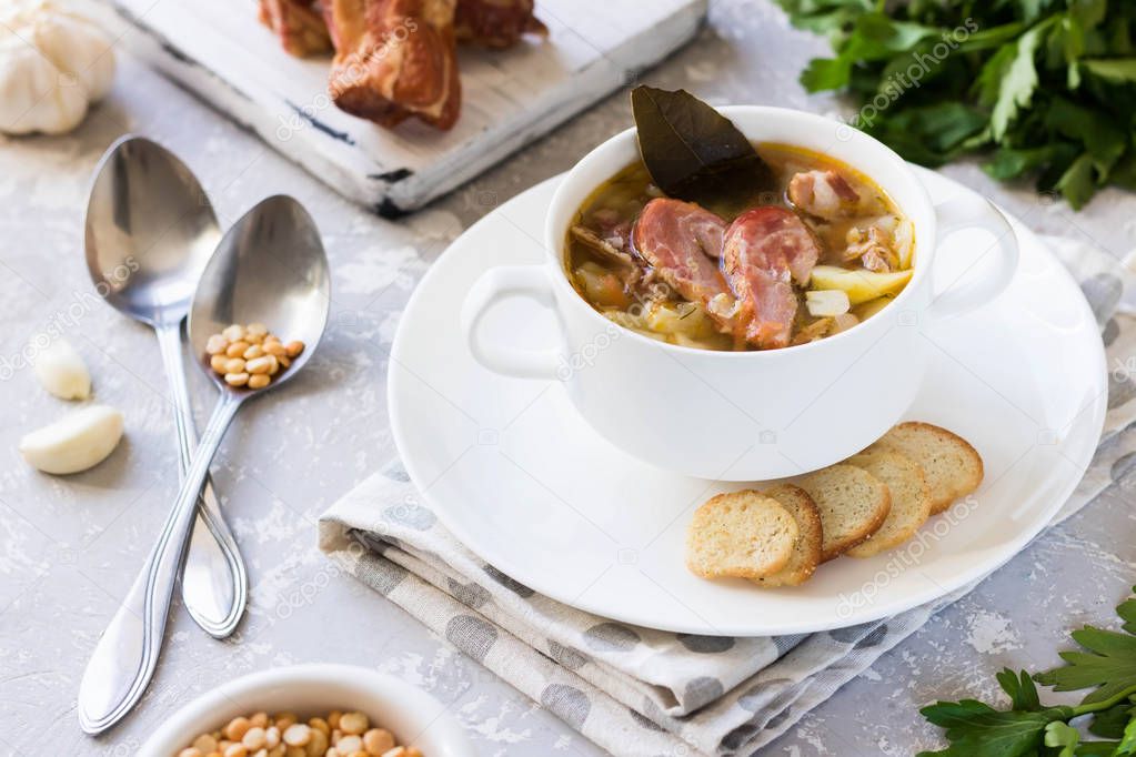 Traditional homemade thick pea soup with smoked meat in a white plate for a family dinner