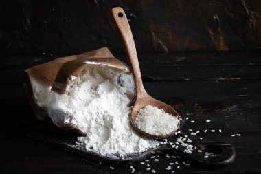 Koyu ahşap bir arka planda el yapımı poşette beyaz pirinç unu.