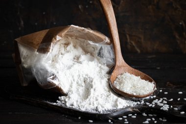 Koyu ahşap bir arka planda el yapımı poşette beyaz pirinç unu.