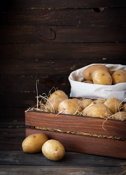 Batatas cruas orgânicas em uma caixa de madeira em palha — Fotografia de Stock