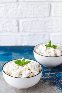 Beyaz kase hafif bir arka plan üzerinde nane yaprakları ile Süzme peynir