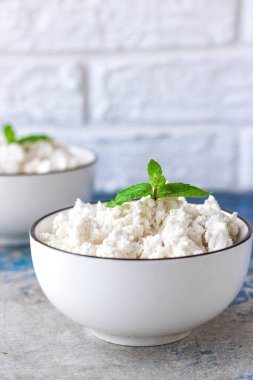 Beyaz kase hafif bir arka plan üzerinde nane yaprakları ile Süzme peynir