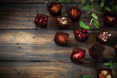 Çeşitli dolgularla ev yapımı çikolatalı tatlılar. Koyu tahta arkaplan.