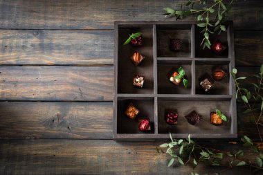 Çeşitli dolgularla ev yapımı çikolatalı tatlılar. Koyu tahta arkaplan.