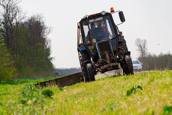 Tractor with a mechanical mower mowing grass