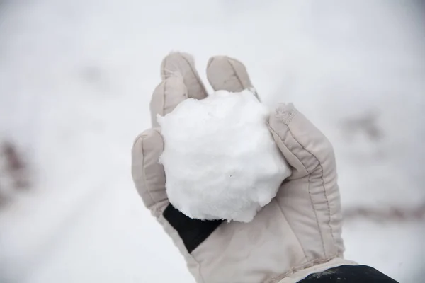real snowballs with their hands clasped from the fresh snow in winter on the street
