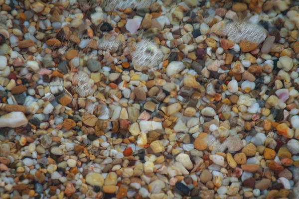 海の小石は ビーチの背景石に花崗岩を着色しました 海の波に洗われた砂と小石のビーチの海岸 — ストック写真