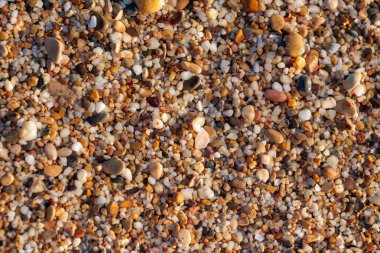 sahil arka plan taşları üzerinde deniz çakıl renkli granit. Kum ve çakıl taşlarıyla sahilin kıyısı deniz dalgalarıyla yıkanmış..