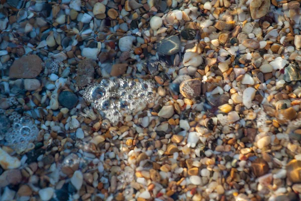 海の小石は ビーチの背景石に花崗岩を着色しました 海の波に洗われた砂と小石のビーチの海岸 — ストック写真