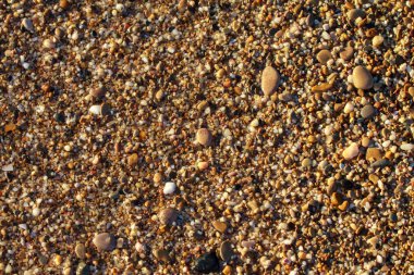 sahil arka plan taşları üzerinde deniz çakıl renkli granit. Kum ve çakıl taşlarıyla sahilin kıyısı deniz dalgalarıyla yıkanmış..