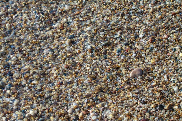 海の小石は ビーチの背景石に花崗岩を着色しました 海の波に洗われた砂と小石のビーチの海岸 — ストック写真
