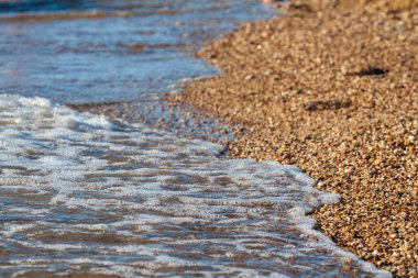 sahil arka plan taşları üzerinde deniz çakıl renkli granit. Kum ve çakıl taşlarıyla sahilin kıyısı deniz dalgalarıyla yıkanmış..