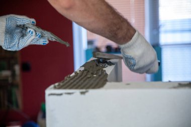 Mason, inşa edilmiş ev duvarının havalandırmalı beton bloğunu hizalıyor.