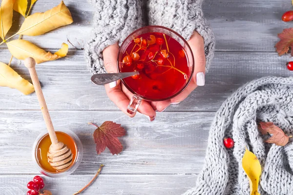 Egészséges viburnum tea mézzel női kéz a kézben a szürke fából készült asztal. Szemközti nézet — Stock Fotó