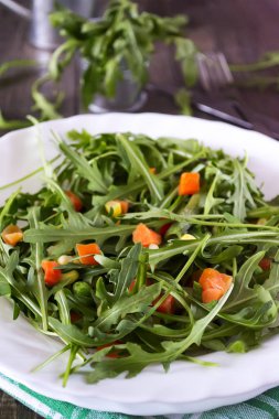 Taze organik roka havuç adet ahşap bir masa üzerinde beyaz bir tabak içinde. Sağlıklı vejetaryen yemek.