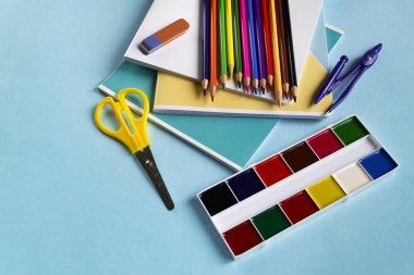 Bir kopya alanı ile mavi bir arka planda Notebook, makas, kalem, pusula ve suluboya okul için ayarlayın.