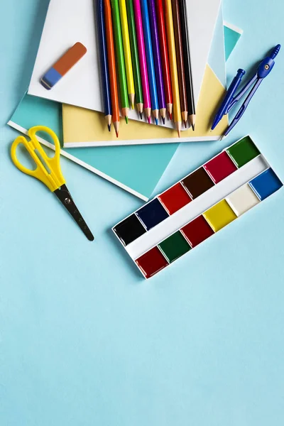 Scissors, dividers, pencils, notebooks and watercolors on a blue background with copy space. School set. Top view — Stock Photo, Image