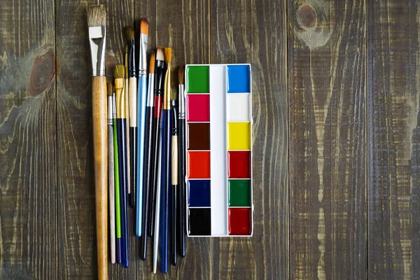 Eine Palette von Aquarellfarbe und ein Pinsel zum Malen auf einem dunklen Holztisch mit Kopierraum. flach lag. Kunstkonzept. — Stockfoto