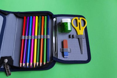 Metin için kopya alanı olan kağıt yeşil arka plan üzerinde bir kalem kasada okul malzemeleri kümesi.