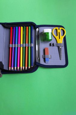 Okul aksesuarları, silgi, kalem, makas, kopya alanı ile kağıt yeşil arka plan üzerinde bir kalem durumda bileyici.