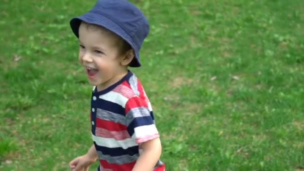 Rapaz feliz correndo na grama no parque — Vídeo de Stock