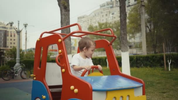 Αγόρι παίζει στο αυτοκίνητο στην παιδική χαρά. — Αρχείο Βίντεο