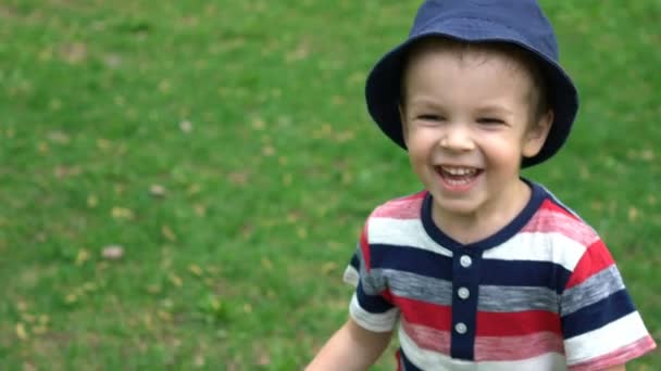 Счастливый мальчик бегает по траве в парке — стоковое видео