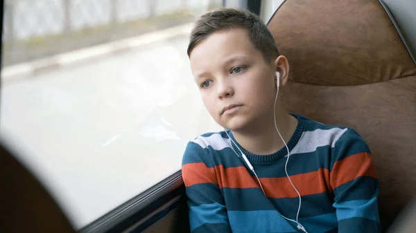 Close-up shot van een jonge jongen die reizen met de bus door de stad. Hij luistert naar muziek. — Stockfoto