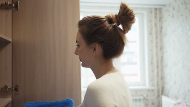 Jovem dona de casa coloca toalhas coloridas no armário — Vídeo de Stock