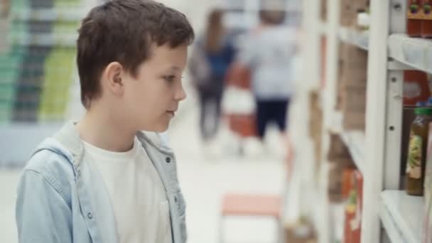 Little boy in the supermarket choose a bottle of juice. — Stock Video