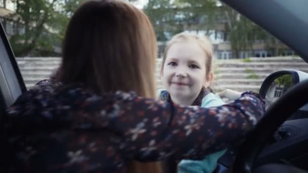 Mamma sitter i bilen och eskorterar sin dotter till skolan. — Stockvideo