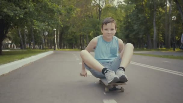 Skateboarder wandelingen in een park met een skateboard. — Stockvideo