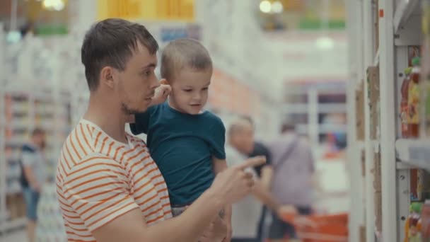 Materiał filmowy ojciec i syn kupić sok w sklepie. — Wideo stockowe