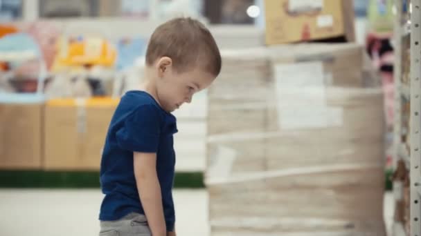 スーパーで小さな男の子はミネラルウォーターのボトルを選択します。. — ストック動画