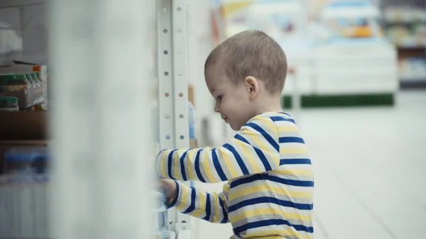 Little boy in the supermarket choose a bottle of mineral water. — Stock Photo, Image