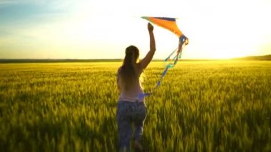 Etrafta dolanan bir uçurtma ile sahada kız.