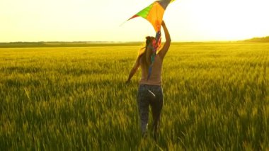 Etrafta dolanan bir uçurtma ile sahada kız.