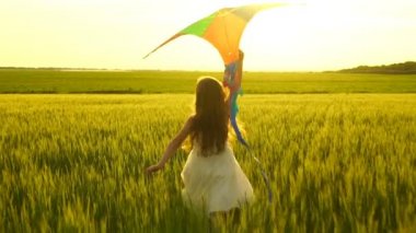 Etrafta dolanan bir uçurtma ile sahada kız.