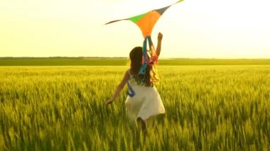 Etrafta dolanan bir uçurtma ile sahada kız.