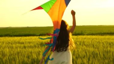 Etrafta dolanan bir uçurtma ile sahada kız.