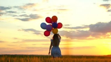gün batımında buğday alanında çalışan balonlu mutlu kadın