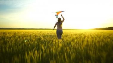 Etrafta dolanan bir uçurtma ile sahada kız.