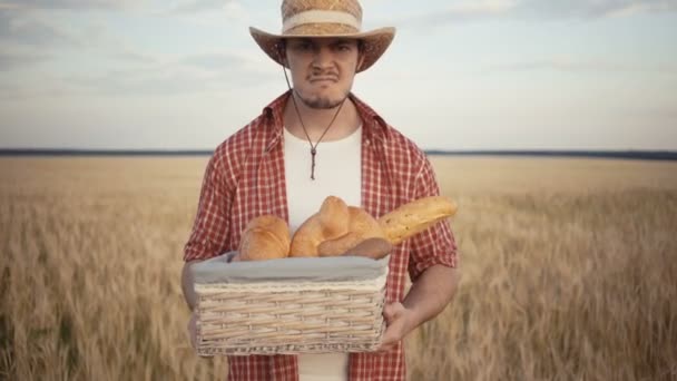 Fiatal mezőgazdasági termelő a stand-mentén a búzamező kenyér kosárral — Stock videók
