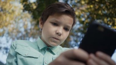 Genç onun smartphone açık havada üzerinde video oyunları oynamak. 4 k görüntüleri
