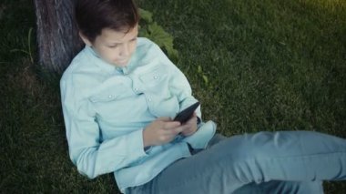 Onun smartphone açık havada üzerinde video oyunları oynarken genç.