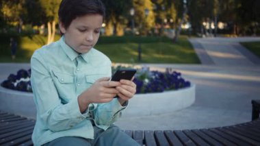 Onun smartphone açık havada üzerinde video oyunları oynarken genç.