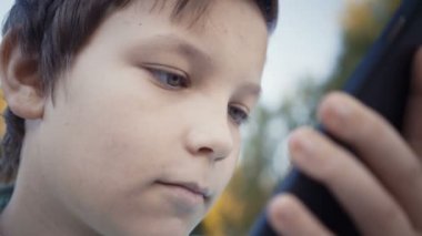 Onun smartphone açık havada üzerinde video oyunları oynarken genç.